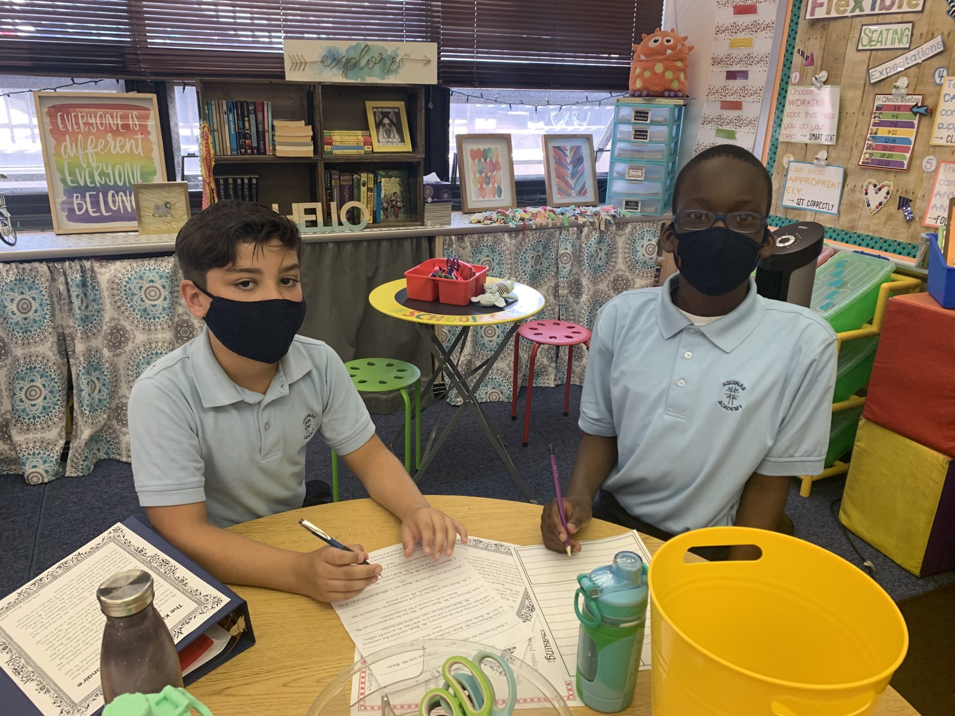 two students wearing masks working on homework
